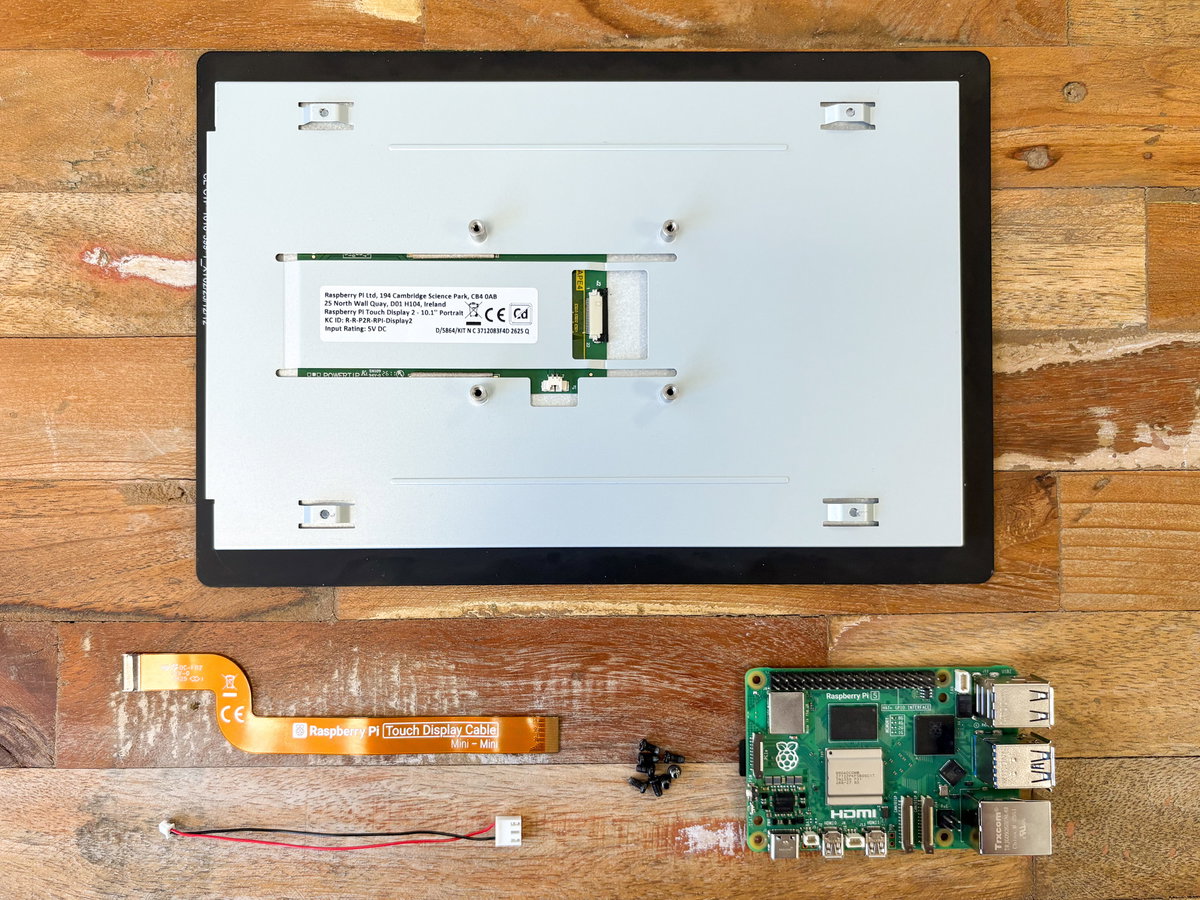 Touch Display 2 parts laid out with ribbon cable, power cable, screws, and Raspberry Pi 5