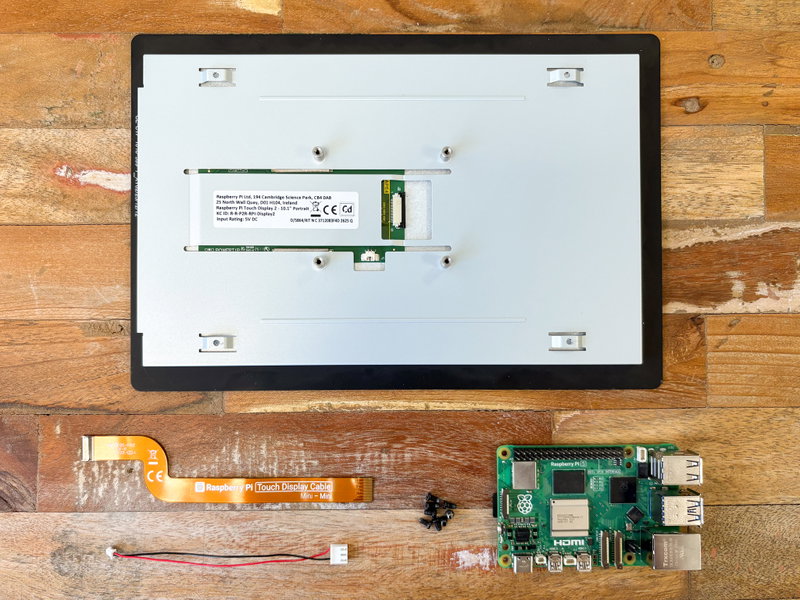 Touch Display 2 parts laid out with ribbon cable, power cable, screws, and Raspberry Pi 5