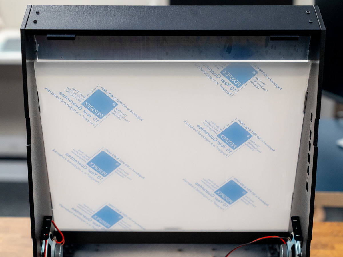 Black cardboard screen surround being fitted beside the acrylic panel